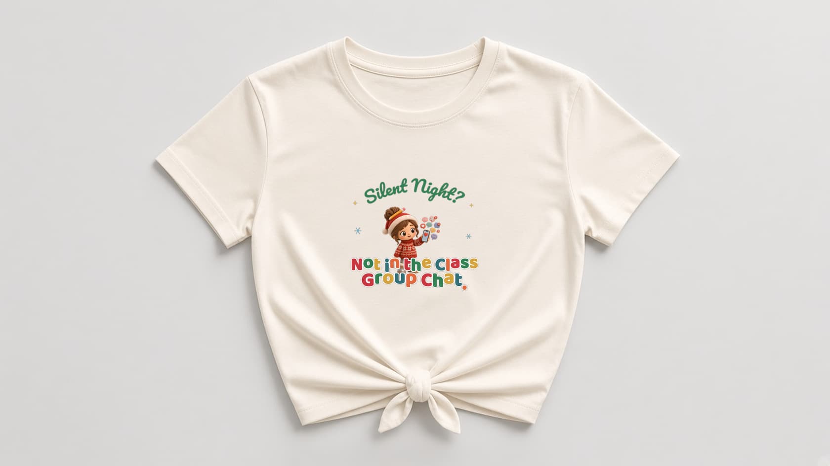 Natural cream knotted women's shirt with a plush chibi room mom in a Santa hat holding a phone full of chat bubbles, under green script "Silent Night?", with multicolor "Not in the Class Group Chat." lettering, gold sparkles and blue snowflakes