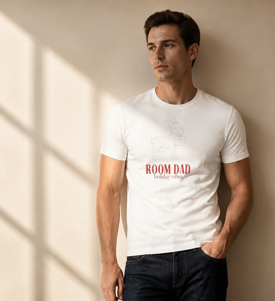 Man wearing a white Room Dad Holiday Vibes Christmas shirt with a red outline reindeer in sunglasses holding a present