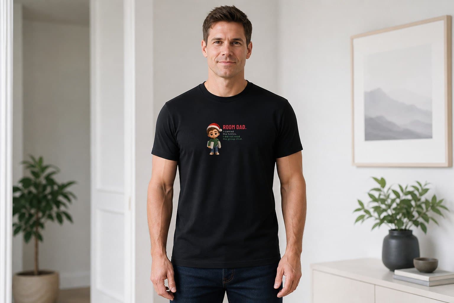 Man wearing a black Room Dad I Carried the Tables Christmas shirt with red, cream and green deadpan lettering and a plush dad carrying tables