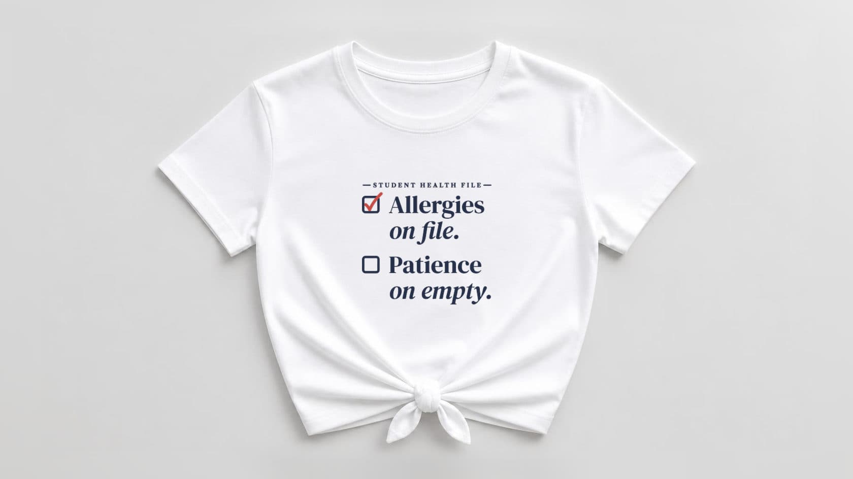 White knotted women's tee with "Allergies on file. Patience on empty." in big navy serif, a red check in the first box and an empty second box