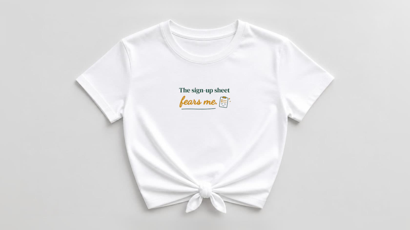 White knotted women's tee with "The sign-up sheet" in evergreen green serif, "fears me." in marigold yellow script over an evergreen swash, and a small worried clipboard