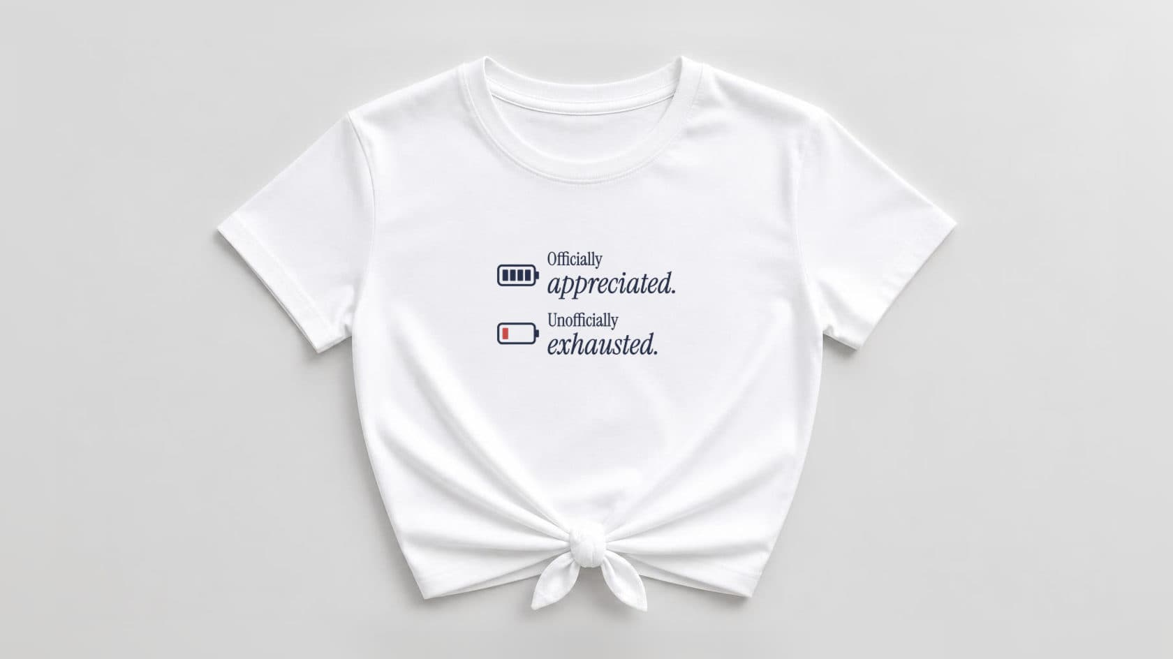 White knotted women's tee printed with "Officially appreciated. Unofficially exhausted." in navy serif beside a full navy battery and a low red battery