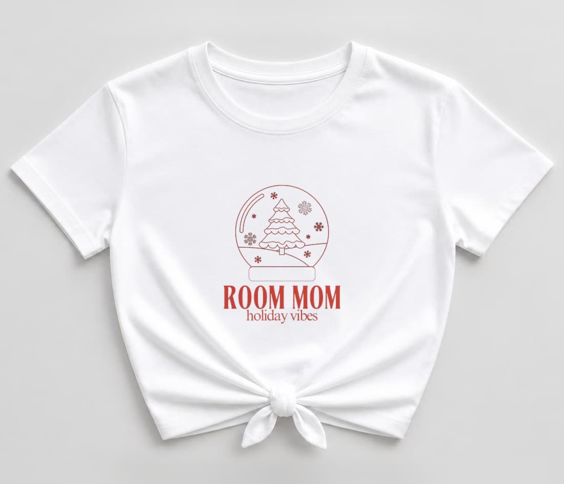 White knotted women's shirt with a red line-drawn snow globe holding a frosted Christmas tree and snowflakes, above "ROOM MOM" and "holiday vibes" in Christmas red